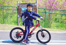 騎著兒童版山地車帶上專業(yè)護(hù)具在青西郊野公園里騎行